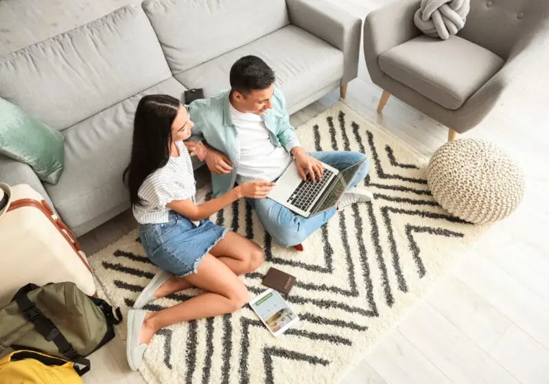 Young couple booking tickets and room in hotel online at home